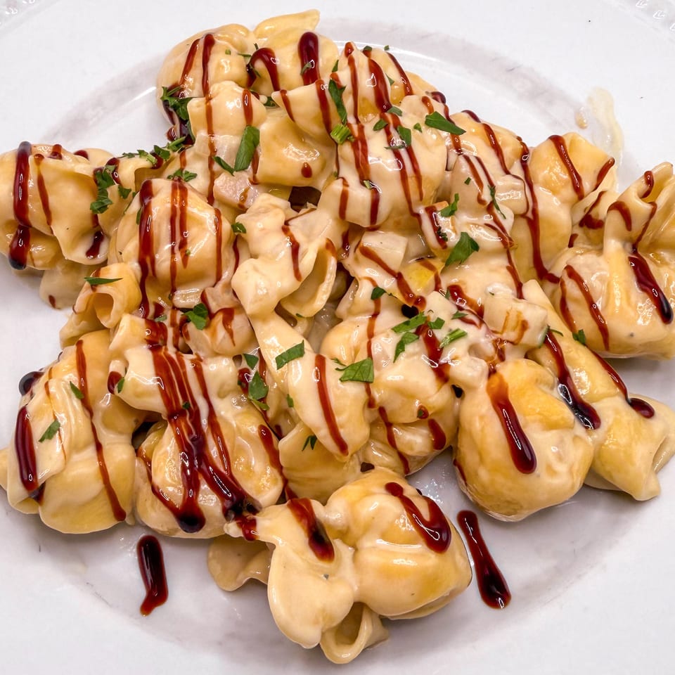 Close-up of pasta shells covered in creamy sauce, drizzled with balsamic glaze and fresh parsley.