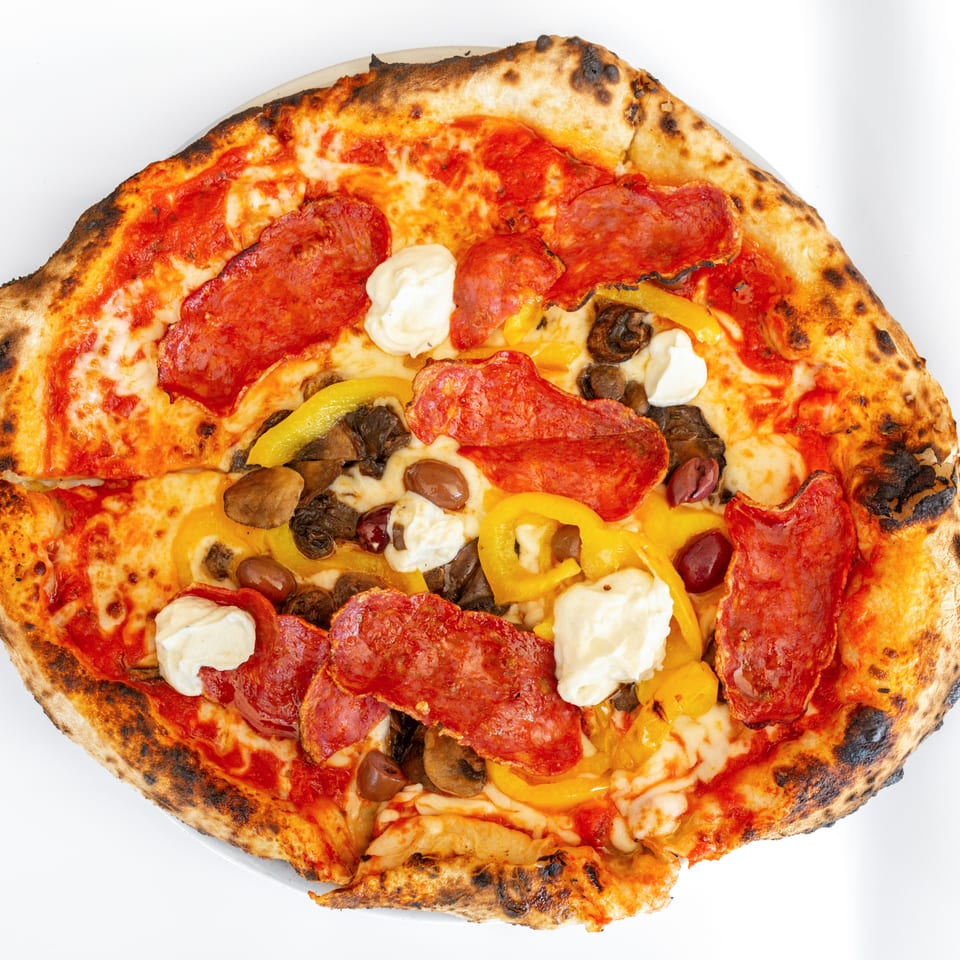 Neapolitan pizza with pepperoni, yellow peppers, mushrooms, olives, and dollops of ricotta cheese.