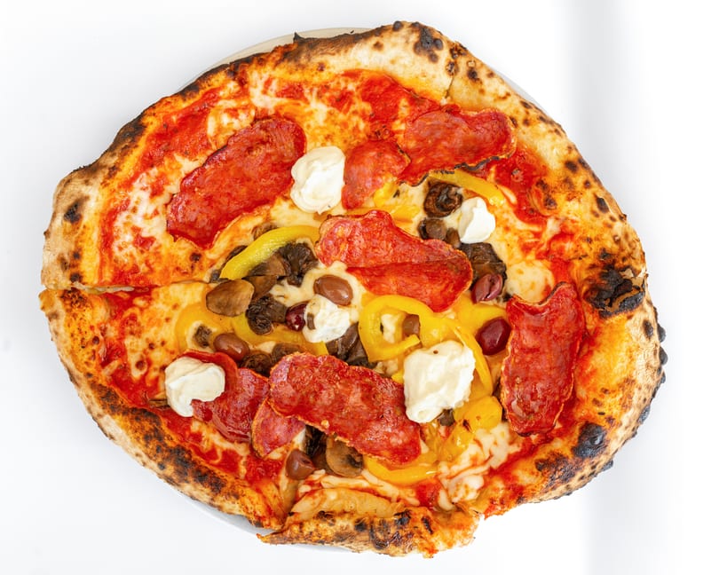 Neapolitan pizza with pepperoni, yellow peppers, mushrooms, olives, and dollops of ricotta cheese.