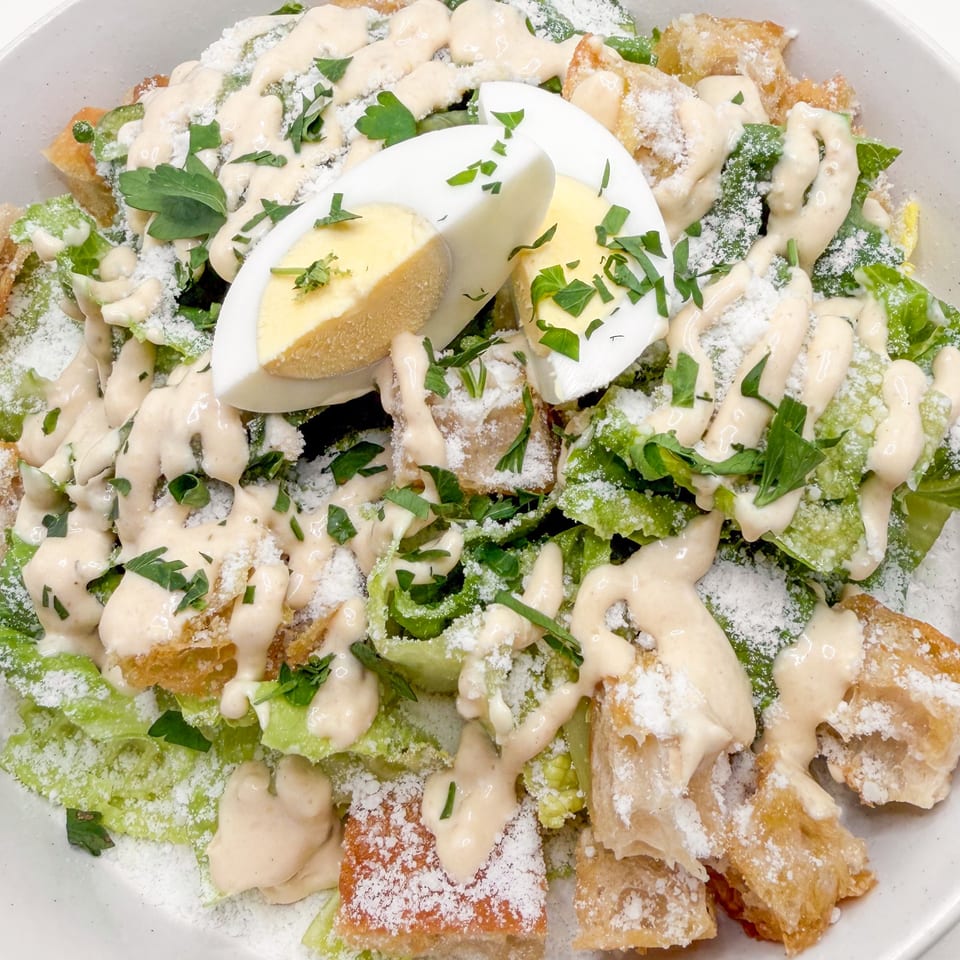 Caesar salad with romaine lettuce, croutons, parmesan, creamy dressing, parsley, and hard-boiled egg.
